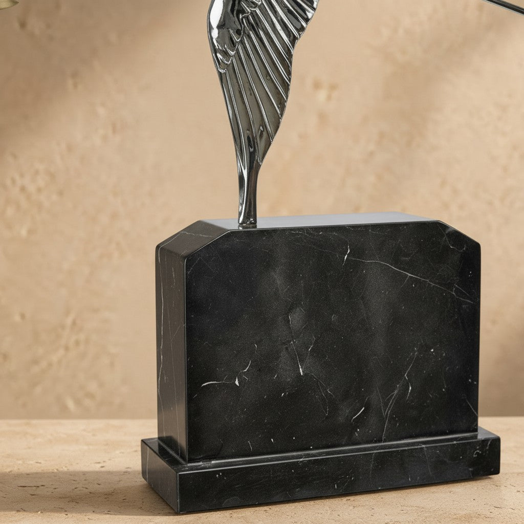 Socle en marbre noir veiné de la sculpture représentant une hirondelle en bronze argenté