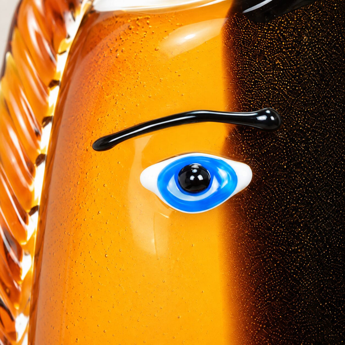 Vase visage abstrait en verre style Murano orange et noir, détail œil bleu gros plan
