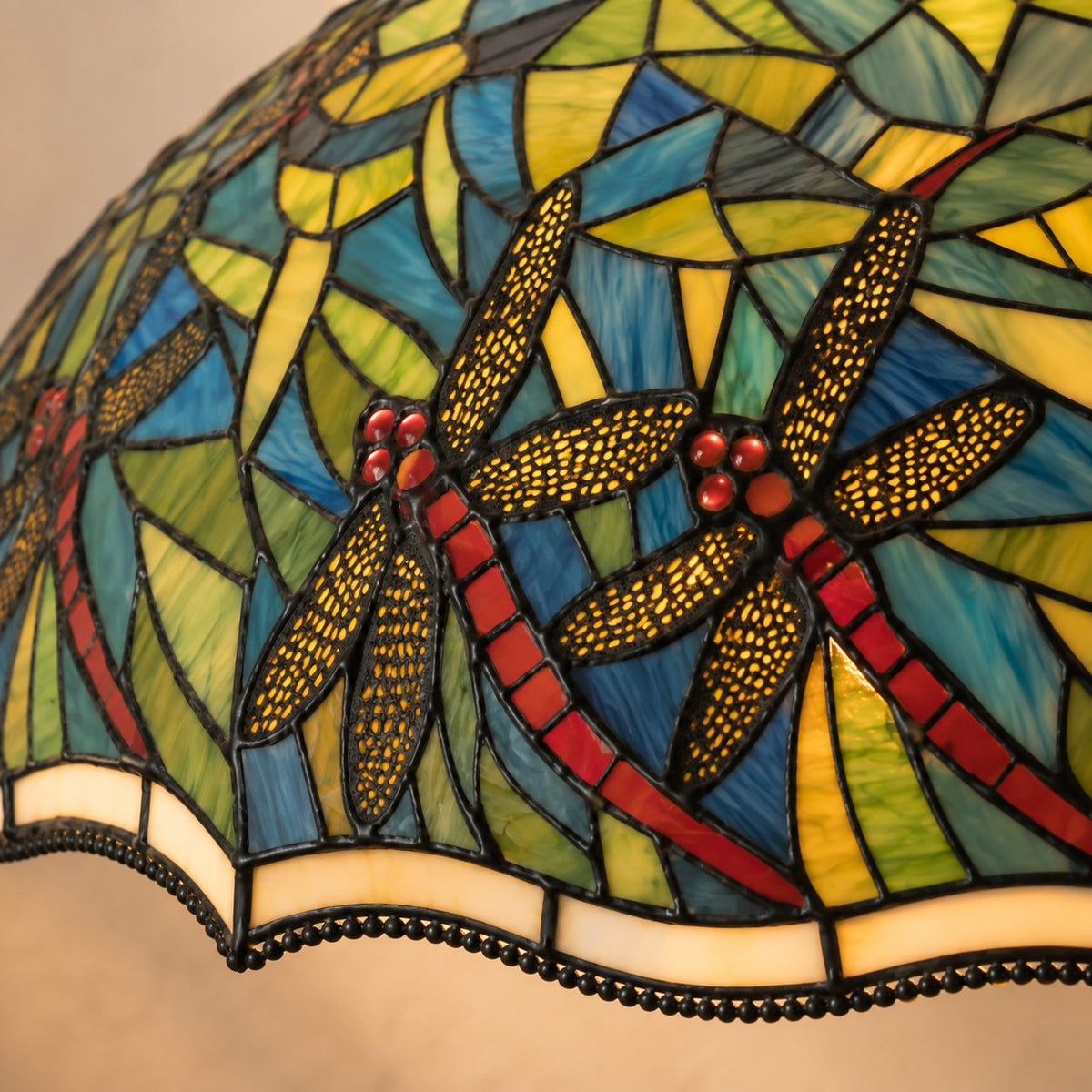 Lampe de style Tiffany aux libellules sur fond de feuillage, gros plan bord feston