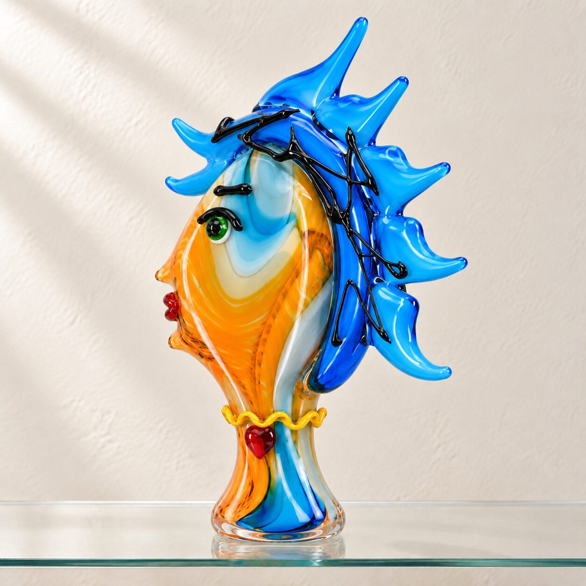 Visage féminin stylisé en verre soufflé bleu cobalt, détail de l'œil en spirale