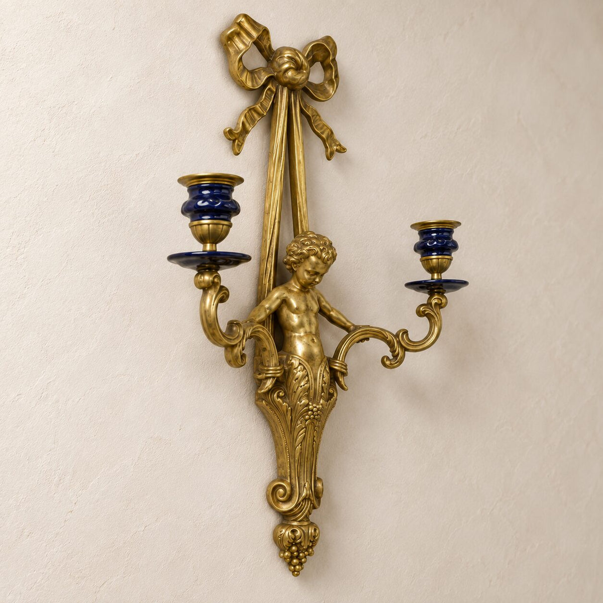 Applique murale au putto en bronze doré et porcelaine bleue, détail putto bras bougeoir gros plan