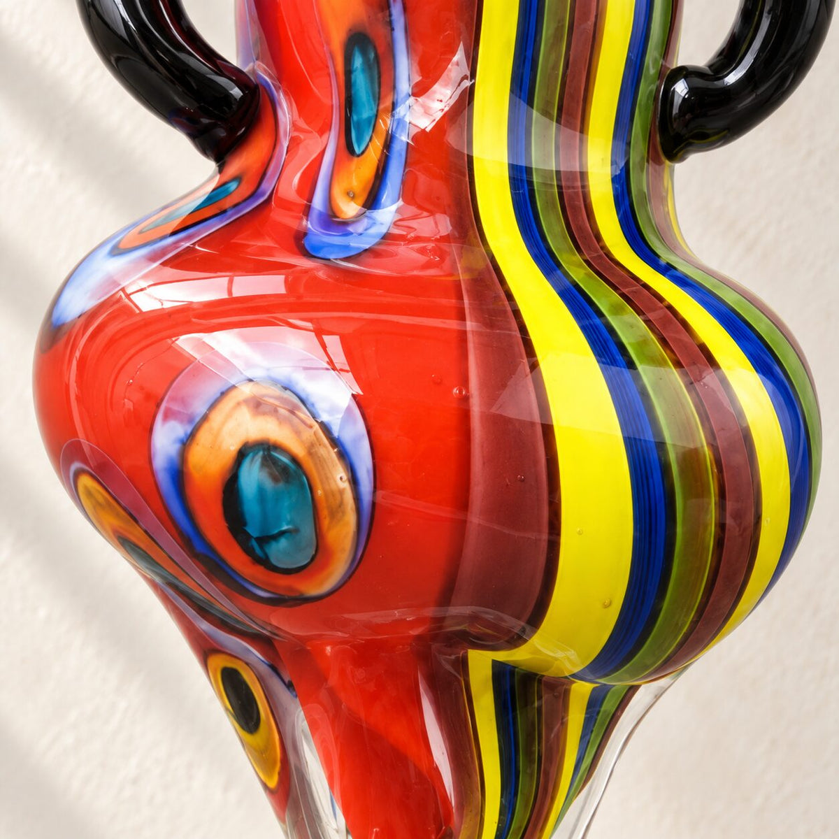 Sculpture femme en verre soufflé style Murano, détail motif œil paon rouge gros plan