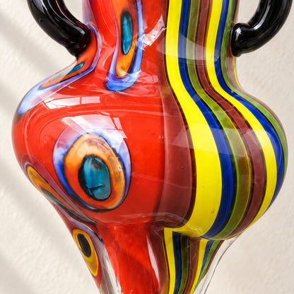 Sculpture femme en verre soufflé style Murano, détail motif œil paon rouge gros plan