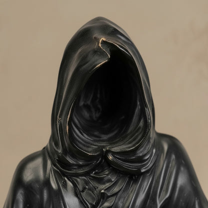 Gros plan sur la capuche noire de la sculpture en bronze Faucheuse, allégorie de la mort détaillée