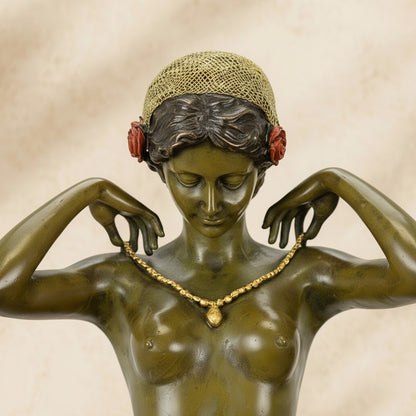 Sculpture en bronze vert-olive représentant une femme agenouillée ajustant un collier doré