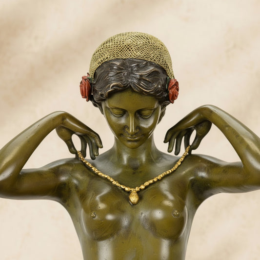 Sculpture en bronze vert-olive représentant une femme agenouillée ajustant un collier doré