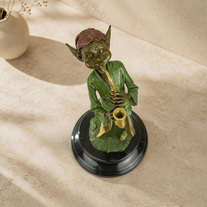 Sculpture en bronze polychrome représentant un lutin jouant du saxophone sur un socle en marbre noir