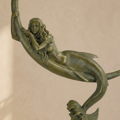 Sculpture en bronze patiné vert-brun représentant une sirène allongée sur un croissant de lune