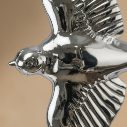 Sculpture d'une hirondelle en bronze argenté brillant avec plumage finement ciselé en plein vol