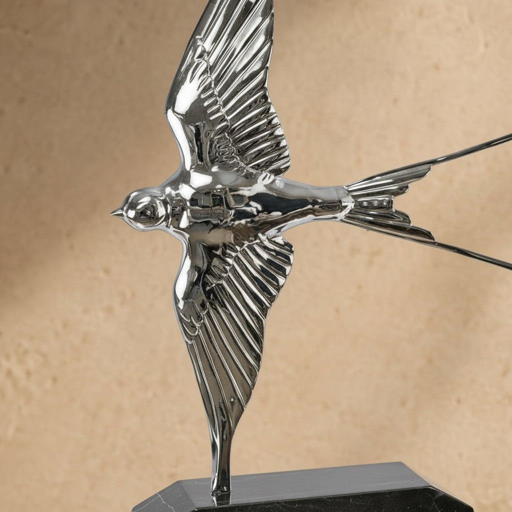 Sculpture hirondelle en bronze argenté brillant aux ailes déployées sur socle en marbre noir