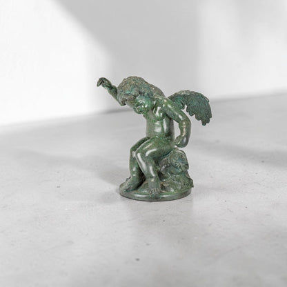 Putto ailé en bronze à patine verte sur socle circulaire