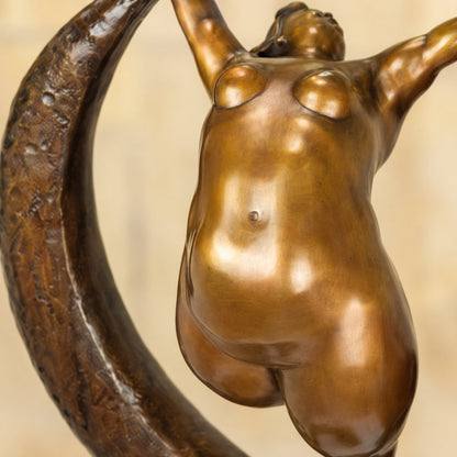 Sculpture bronze femme aux formes généreuses sur croissant de lune, vue rapprochée silhouette
